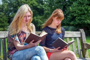 two girls reading books on a bench